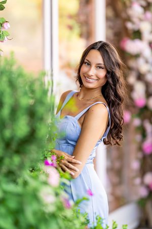 Portrait session in a garden with pink flowers and natural sunlight creating a dreamy summer atmosphere.