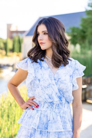 Portrait series in a white and blue ruffled dress against an outdoor setting.