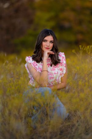 A portrait session in tall grass featuring someone wearing a floral print top at sunset.