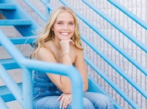 Portrait session against blue stairs showcasing casual denim outfit and natural poses.