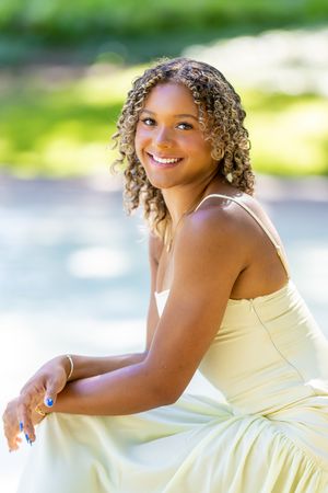 Joyful outdoor photoshoot featuring a yellow sundress against a bright natural background.