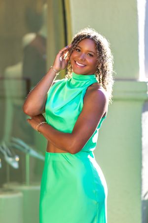 Dynamic poses in a bright mint green dress against a neutral wall.
