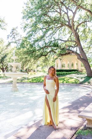 Elegant outdoor portraits in a pale yellow dress under shaded trees.