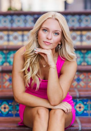 Woman in pink tank top poses on decorative tiled steps.