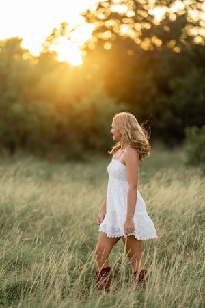 White sundress flowing in golden sunlit field during sunset photoshoot.