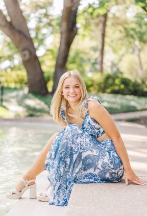 Outdoor portrait series featuring a flowing blue and white floral dress in a sunny garden setting.
