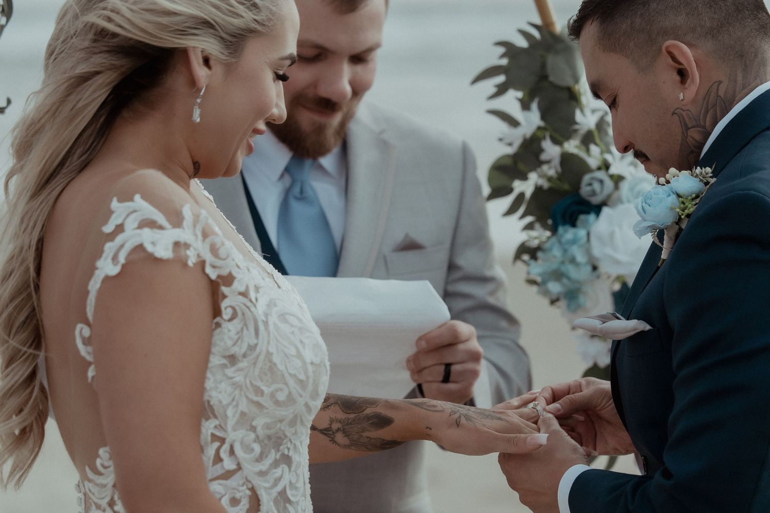 A couple exchanges rings during a wedding ceremony as they stand together in front of an officiant.