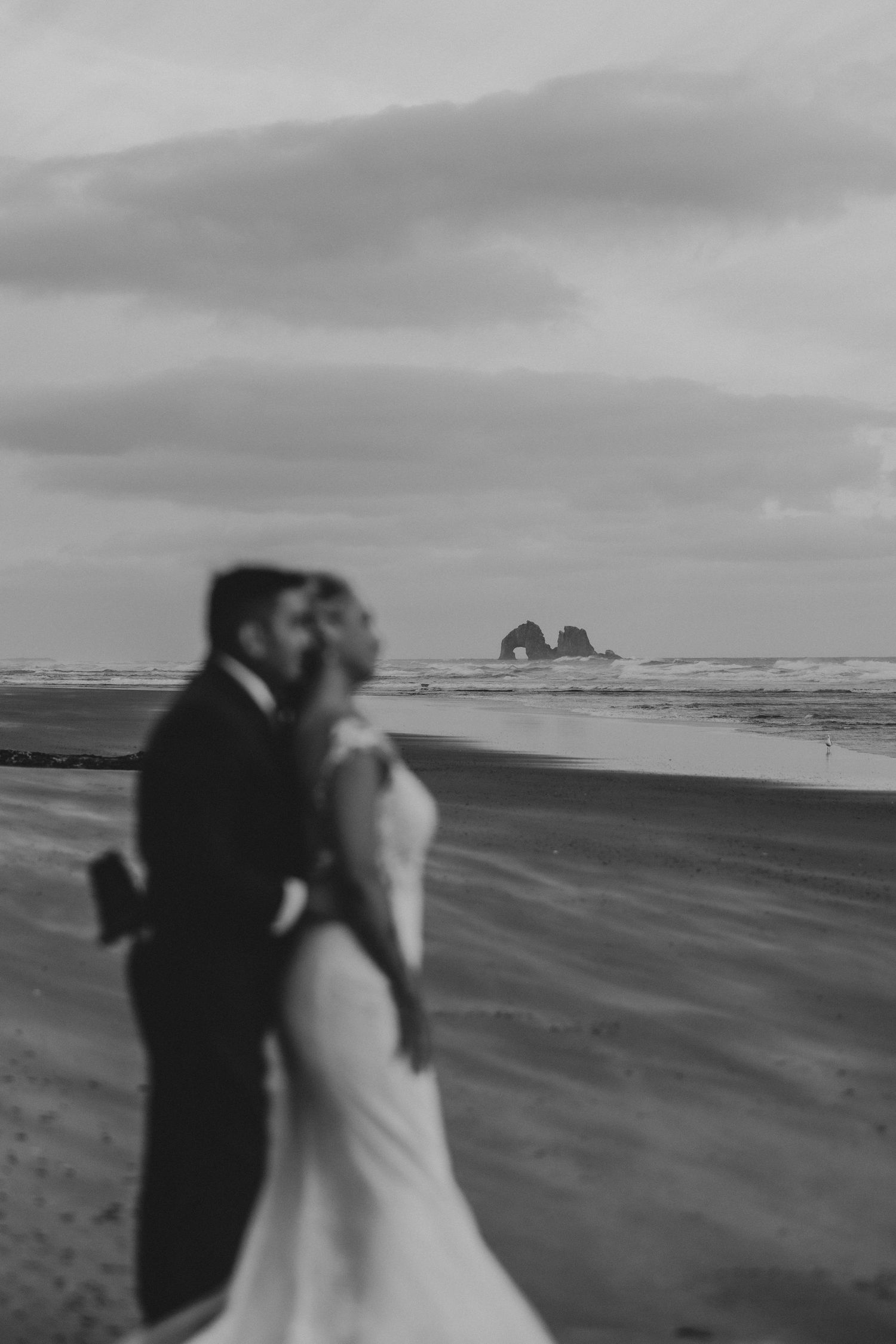 A romantic black and white beach wedding photoshoot sequence of a couple walking along a misty shoreline.