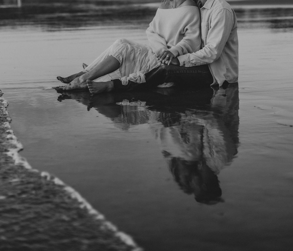 Vintage black and white photograph showing someone fly fishing in a tranquil river with reflections on the water surface.