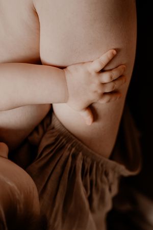 Close-up van een klein babyhandje tegen zachte stof in teder licht.