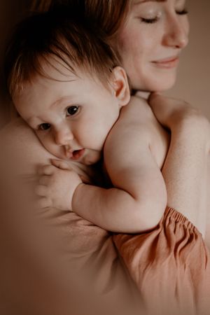 Artistiek portret dat een teder moment tussen verzorger en baby vastlegt in warme sepia-tinten.