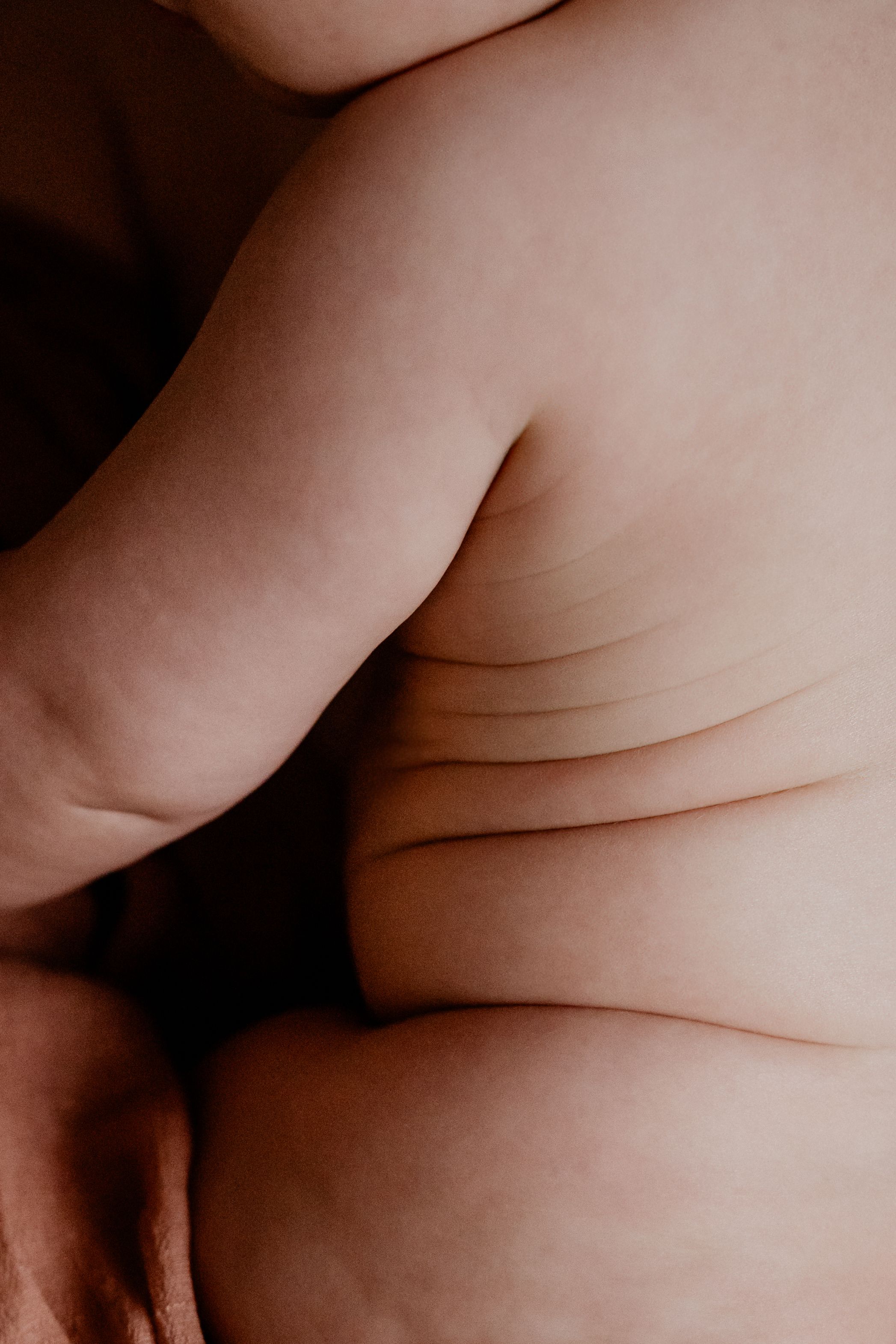 Abstracte close-up van de zachte babyhuid, met natuurlijke plooien en lijntjes, vastgelegd in warm licht.