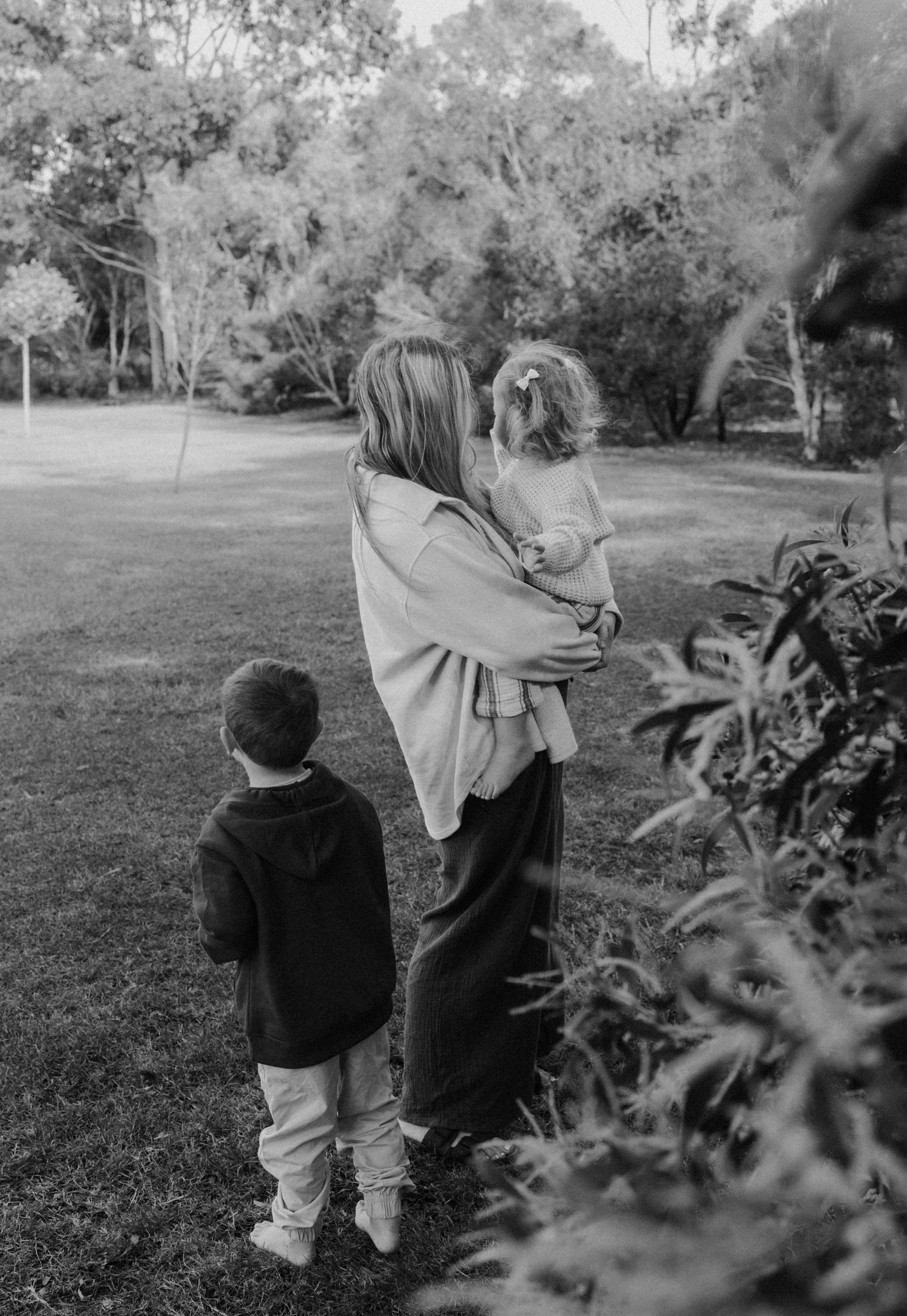 A couple sits on a lawn at sunset in front of a white country home.