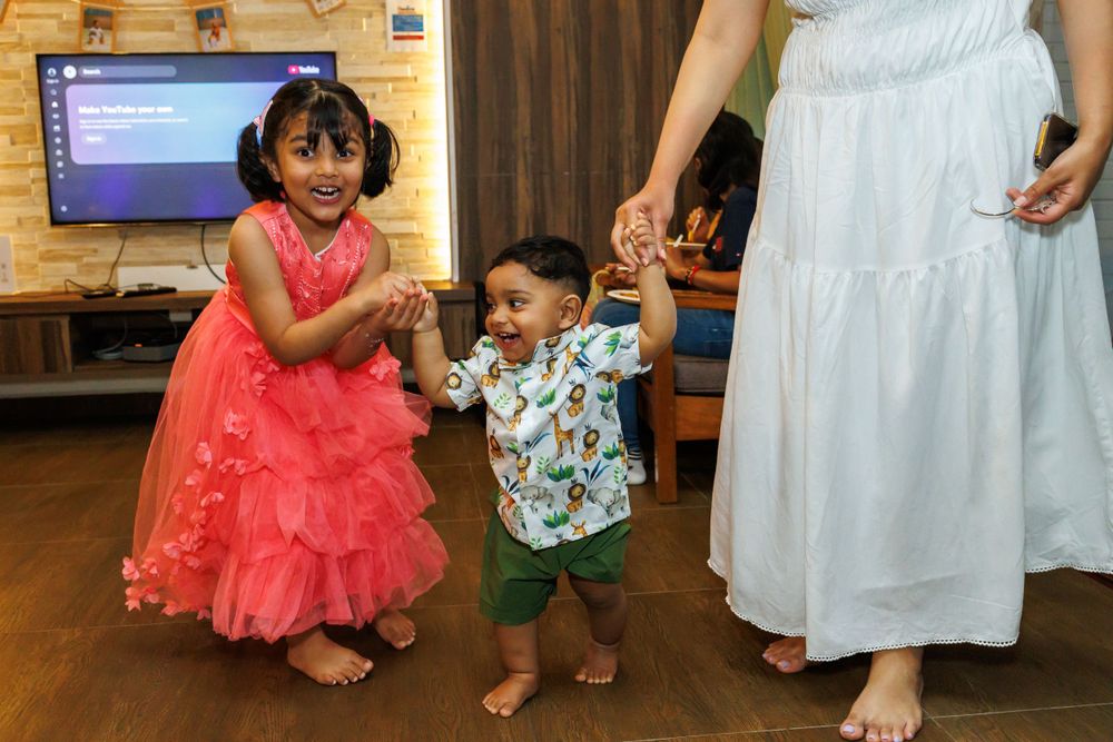 Children dancing together at a party with decorative lighting and wooden floors.