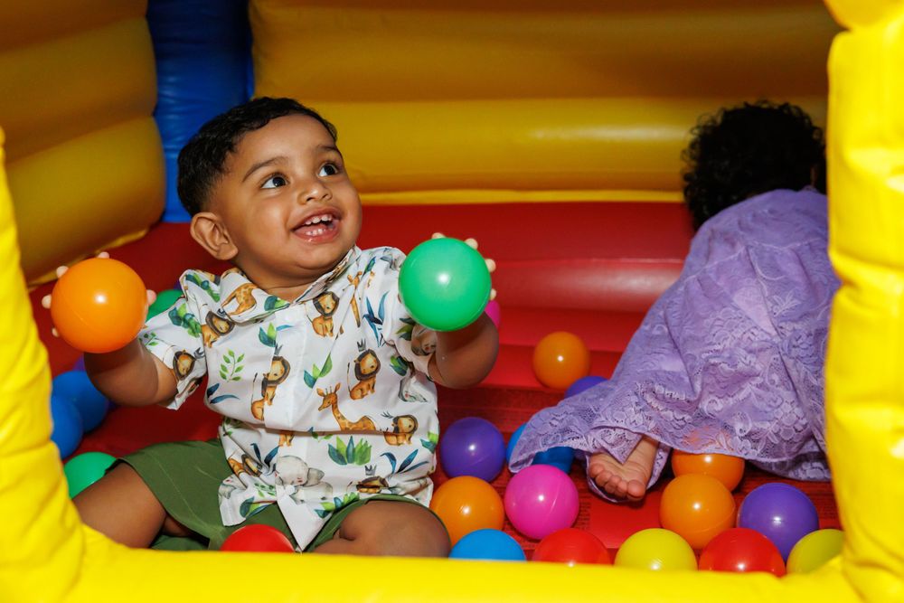 A child enjoys playtime in a bouncy castle filled with colorful balls.