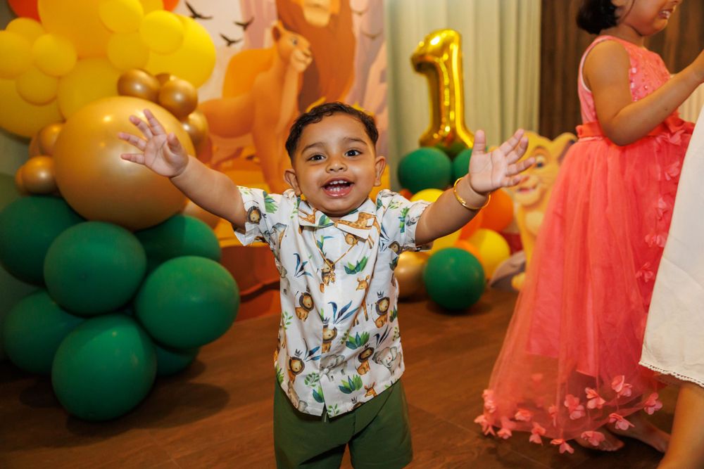 Young child expressing joy at a Lion King themed birthday party with balloon decorations.