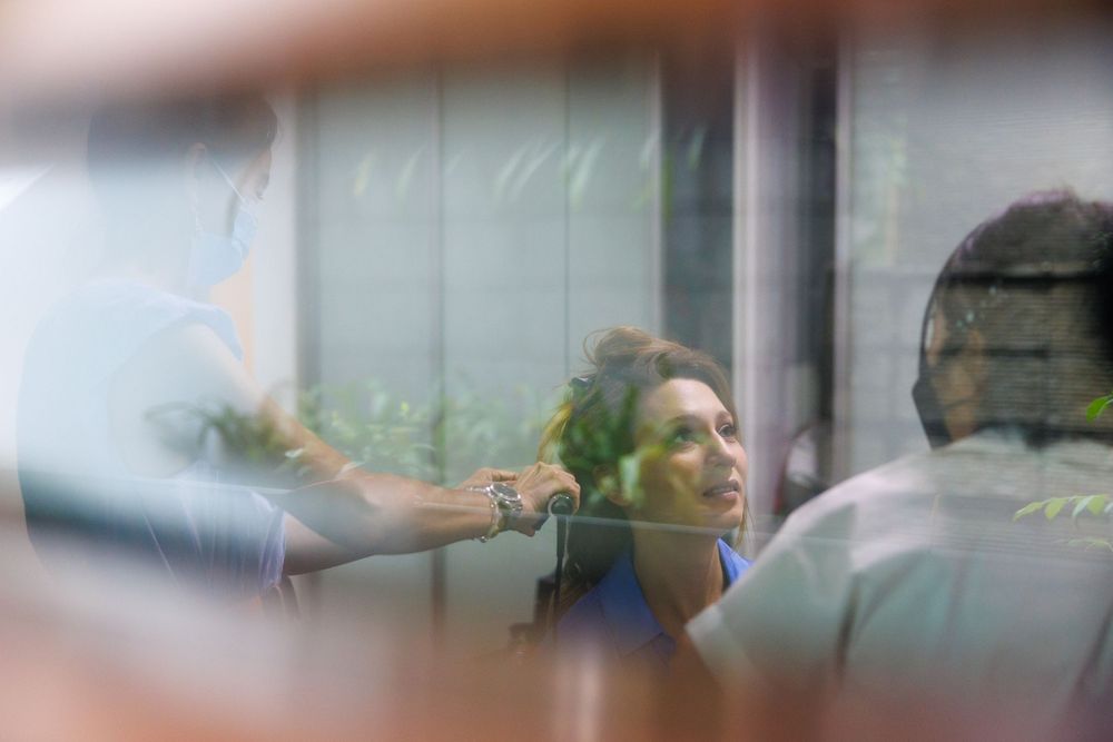 Blurred behind-the-scenes shot through glass of a styling session in progress.