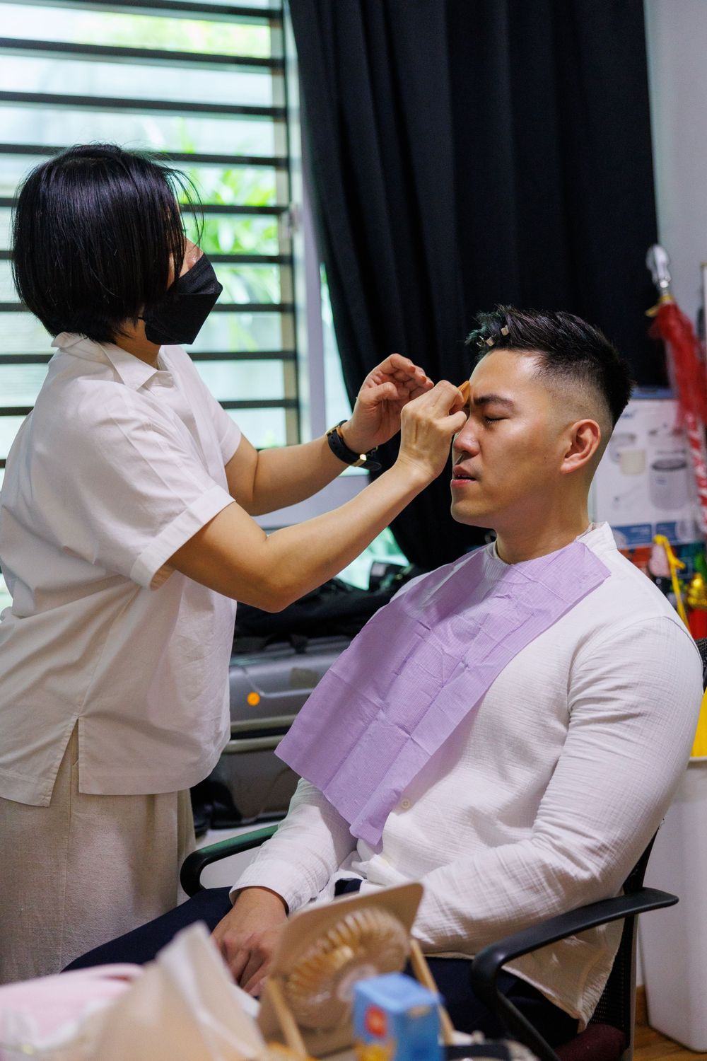 Makeup artist applies cosmetics during wedding preparation session.