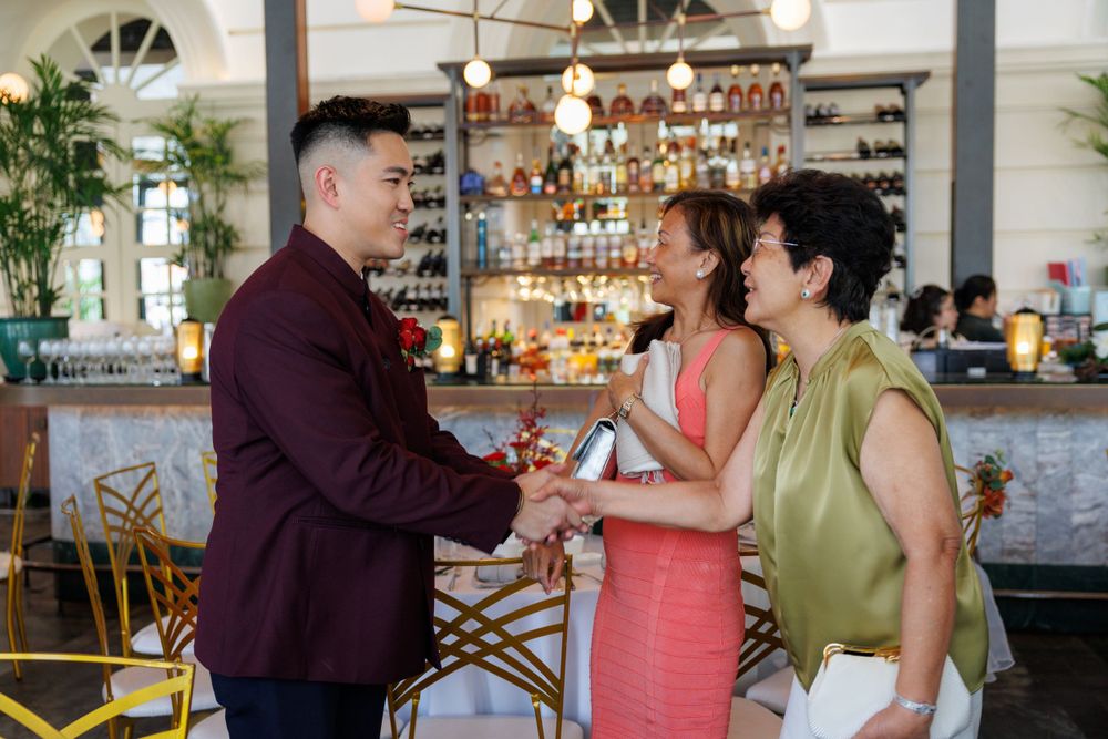 Wedding attendees exchange greetings at a restaurant bar with elegant decor.