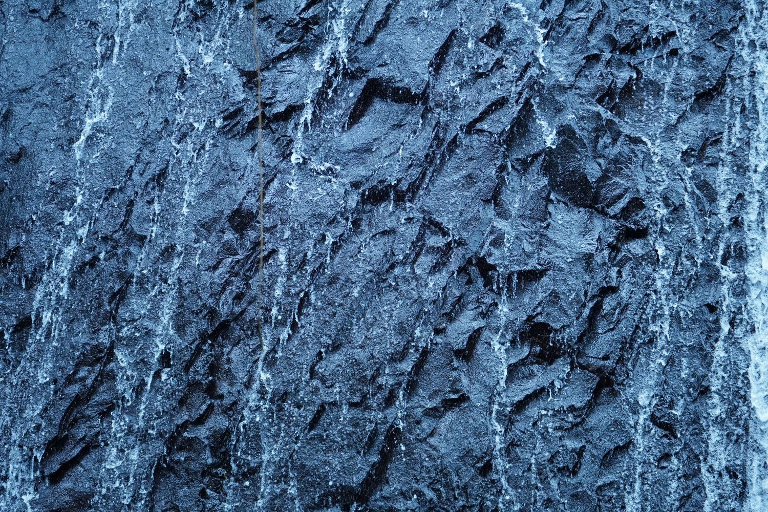 Abstract blue textured rock or ice surface with natural patterns and cracks.