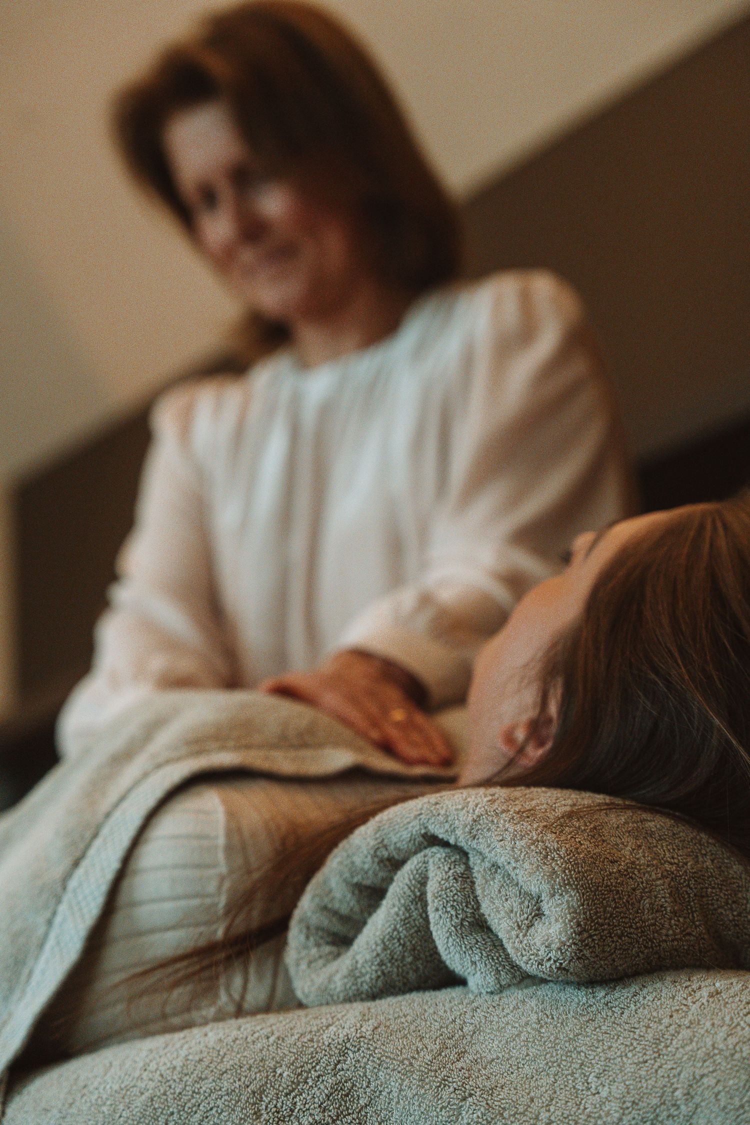 A person in a white sweater gives a relaxing therapeutic massage on a soft gray blanket.