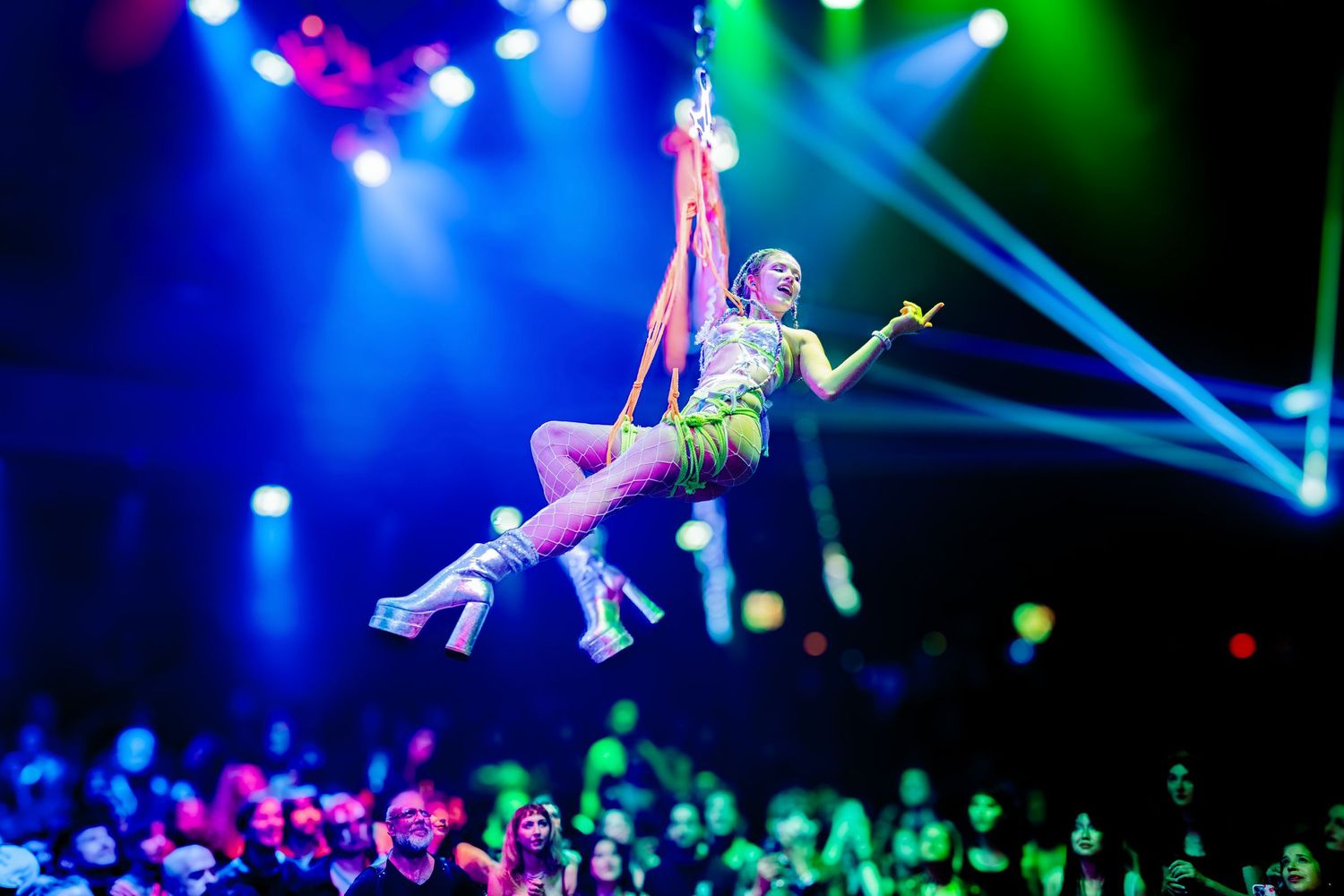 Bondage Ball: a woman dangles via a rope suspension rig over a crowd in a nightclub.