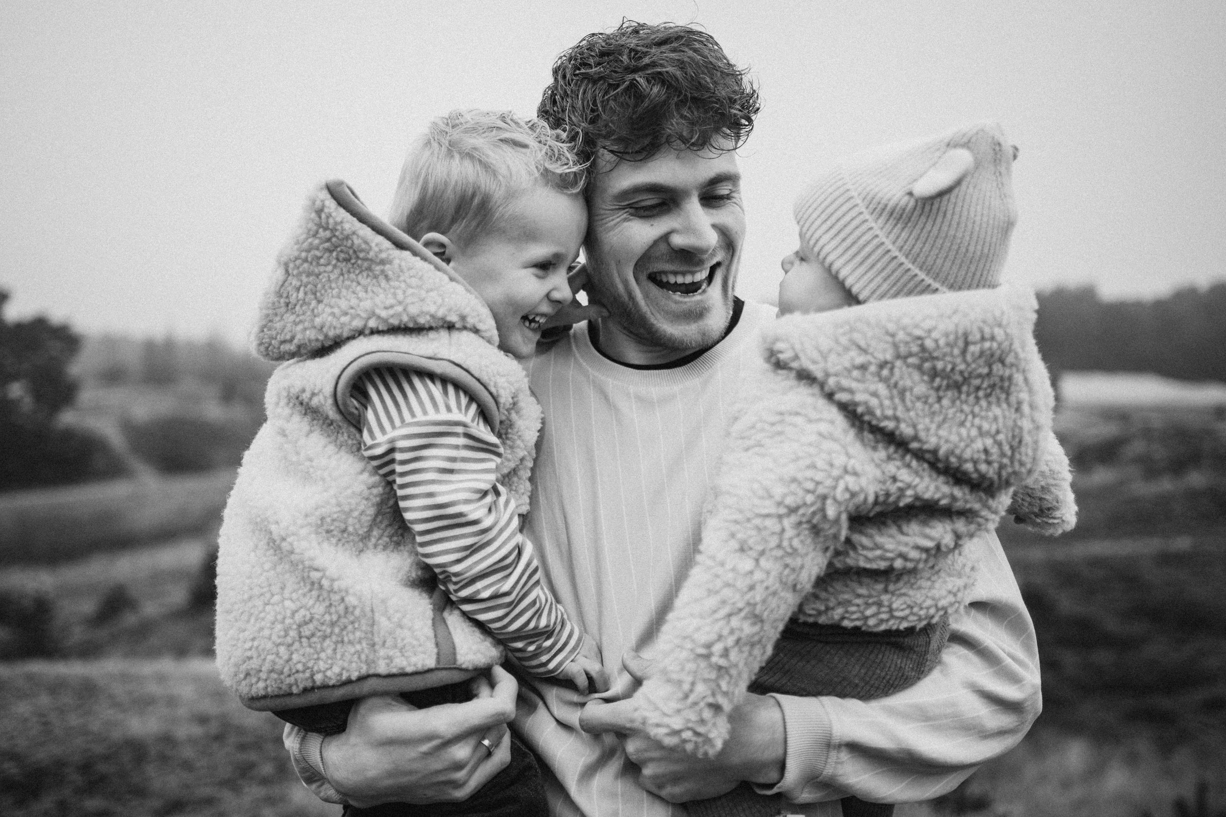 Sweet candid black and white moment showing love and laughter on a hillside.