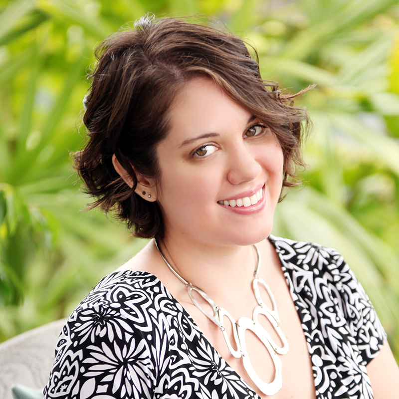 Portrait of woman in patterned top against green foliage background.