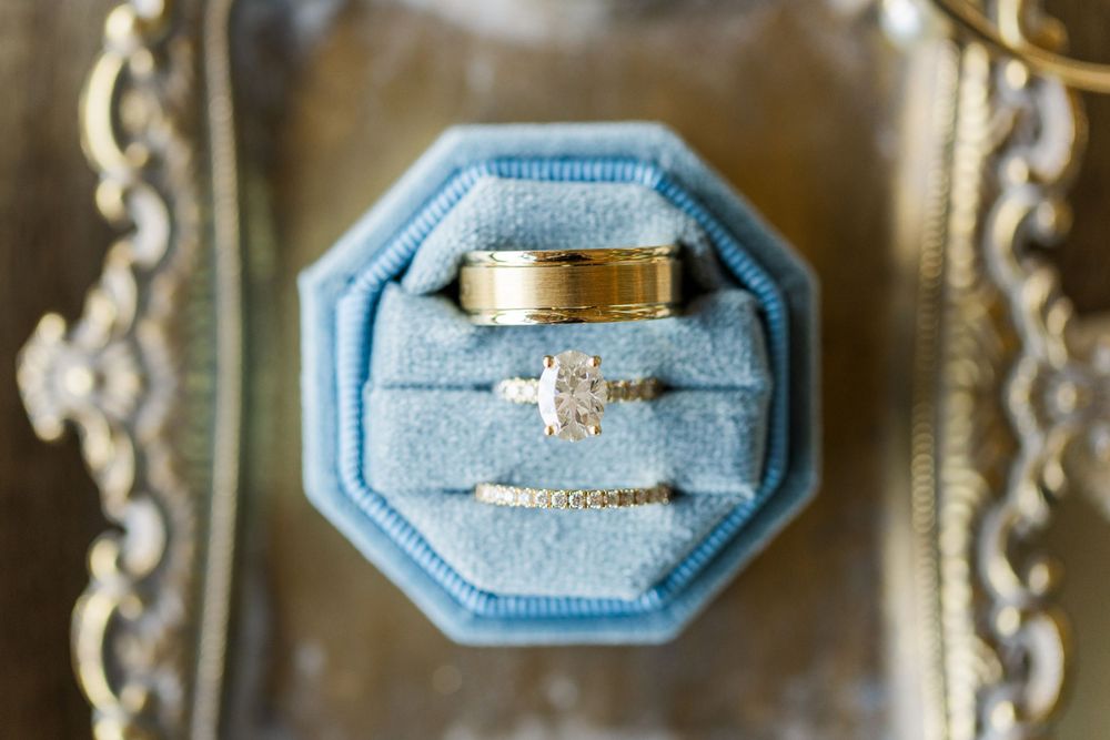Wedding rings displayed in a light blue velvet octagonal ring box on an ornate silver tray.