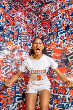 Energetic shot showing a person in white Evanston jersey number 9 against vibrant red and blue patterned background.