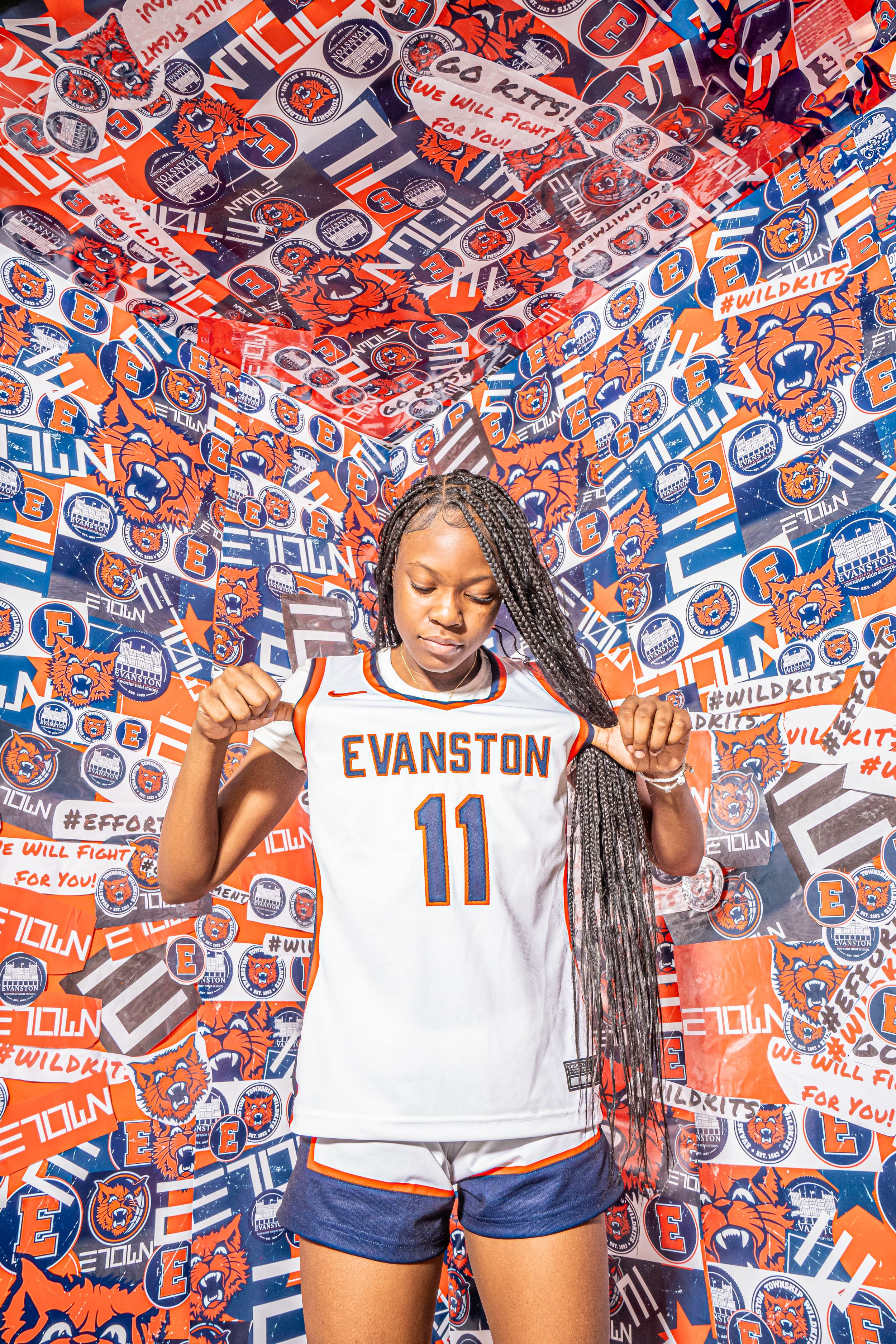 Athletic person in white Evanston #11 jersey poses against orange and blue patterned backdrop displaying team spirit.