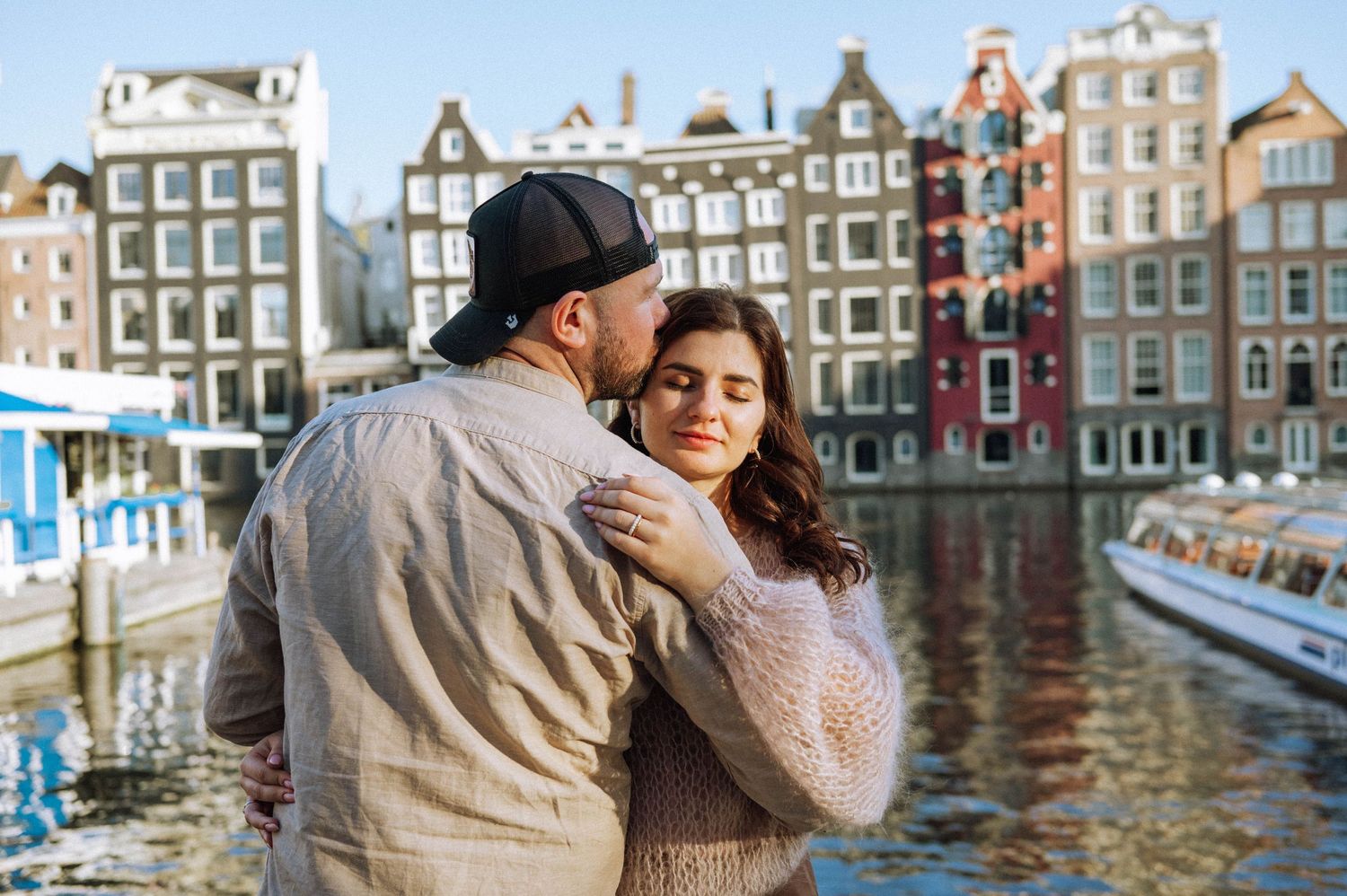 A couple embraces while exploring Amsterdam's picturesque canals and historic architecture.