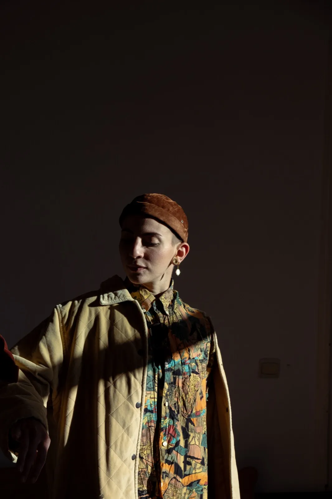 Portrait d’une jeune femme dans la pénombre, éclairé partiellement, regard tourné vers la lumière.