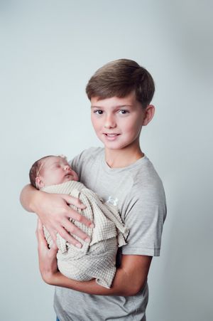 Big brother carefully holding sleeping baby sister