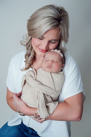 Gentle studio portrait with sleeping newborn baby wrapped in knit blanket.