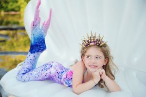 Whimsical mermaid-themed portrait with sparkling costume and crown on shell backdrop.