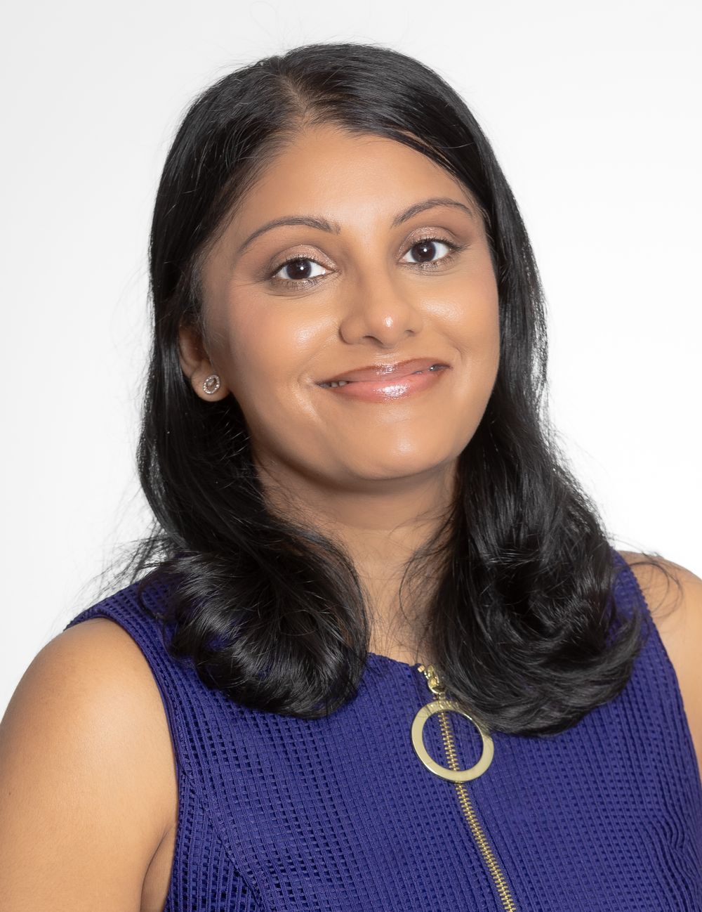 Professional headshot of woman in blue sleeveless top with gold circle pendant.