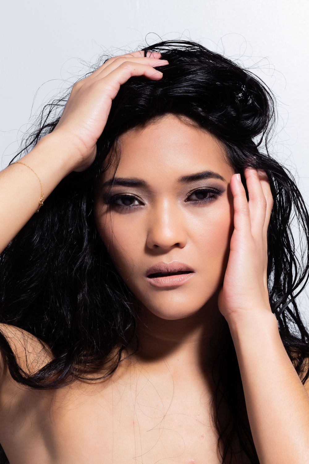 Beauty portrait with dramatic lighting showing hands framing face.