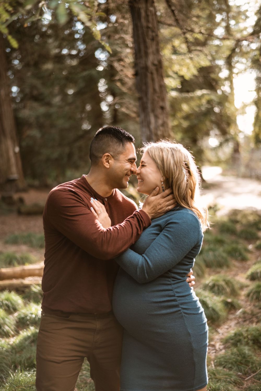 Couple sharing intimate moment in sunlit forest setting.