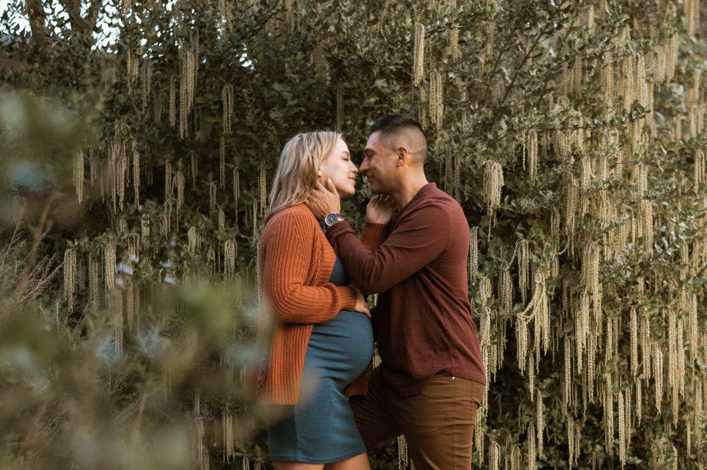 Couple in autumn sweaters embrace tenderly against a backdrop of Spanish moss hanging from trees.