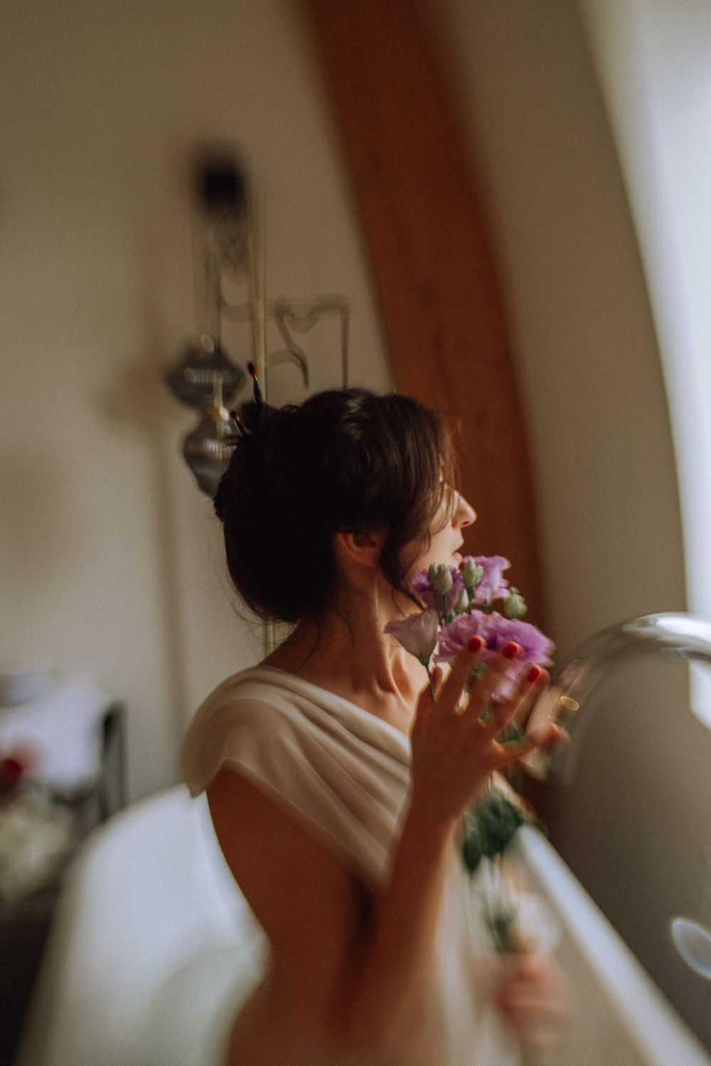 A series of artistic photos showing someone holding pink flowers in soft lighting.