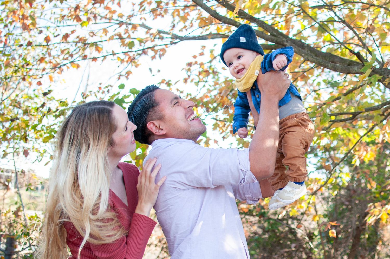 Candid family pose with dad holding infant up