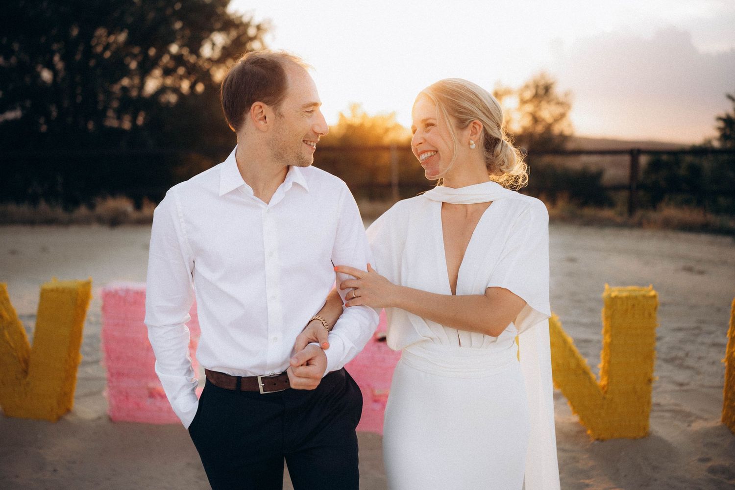 Intimate wedding portrait in a rustic field with bride in white dress and groom in rust-colored suit.