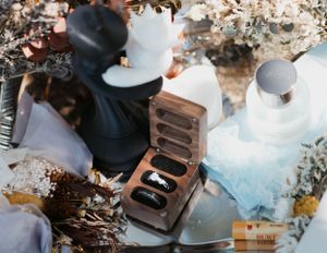 Chess pieces displayed with a wooden ring box and floral arrangements.