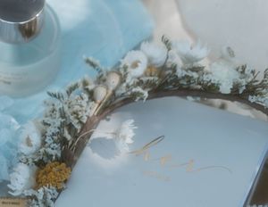 Delicate dried flower crown resting on a light blue book with gold lettering.