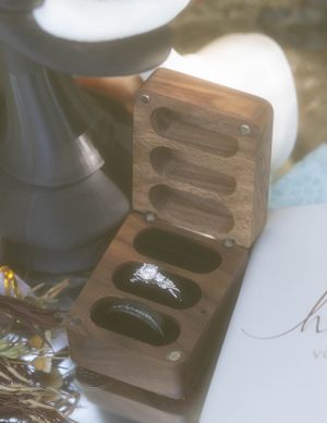 Wooden ring box with diamond engagement ring displayed in natural lighting.