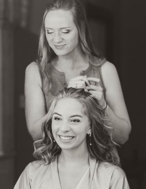 A candid black and white photo of wedding day hair preparation.