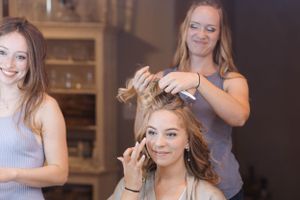 Wedding preparation scene showing styling and makeup application in progress.