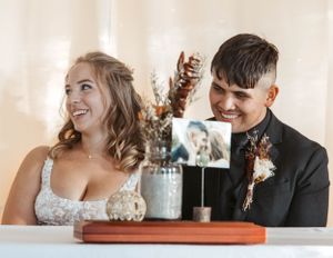 A happy couple shares a joyful moment together at their wedding reception while seated at a decorated table.