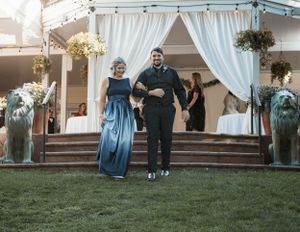 Wedding ceremony exit with couple walking down steps under white draped fabric and floral decorations.